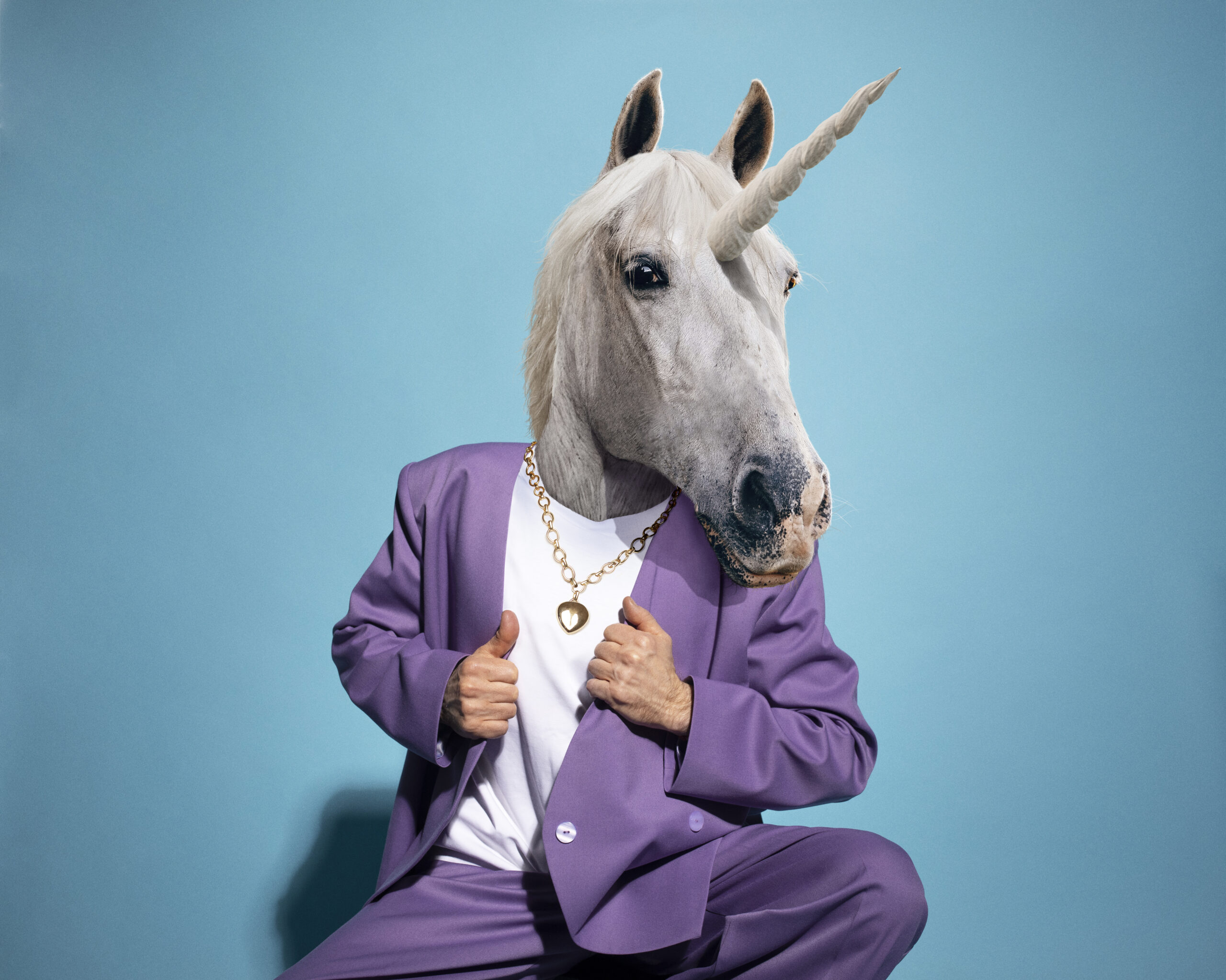 Person with a unicorn head mask wearing a purple suit against a blue background